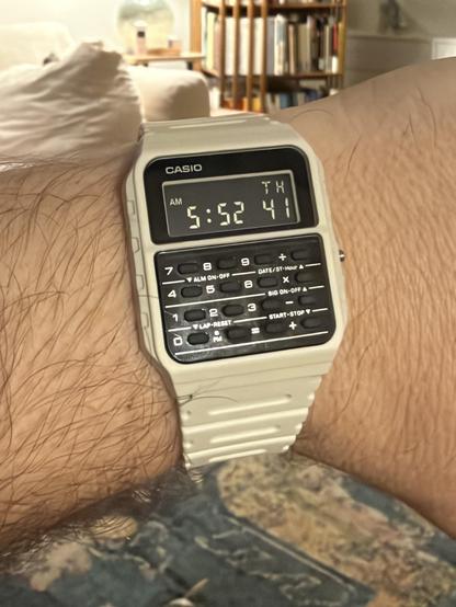 A white band plastic calculator watch with inverted LCD display and black keys