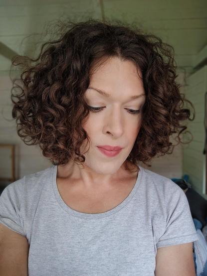 head and shoulders portrait of me, curly brown hair and a grey t-shirt, looking down and outside the picture at my left hand