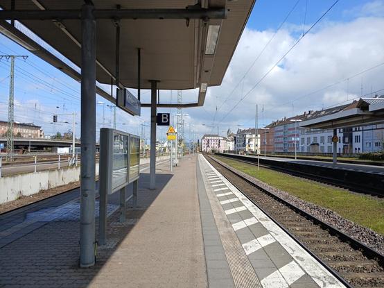 View of the train station. It is mostly empty and the sky is blue with some clouds.